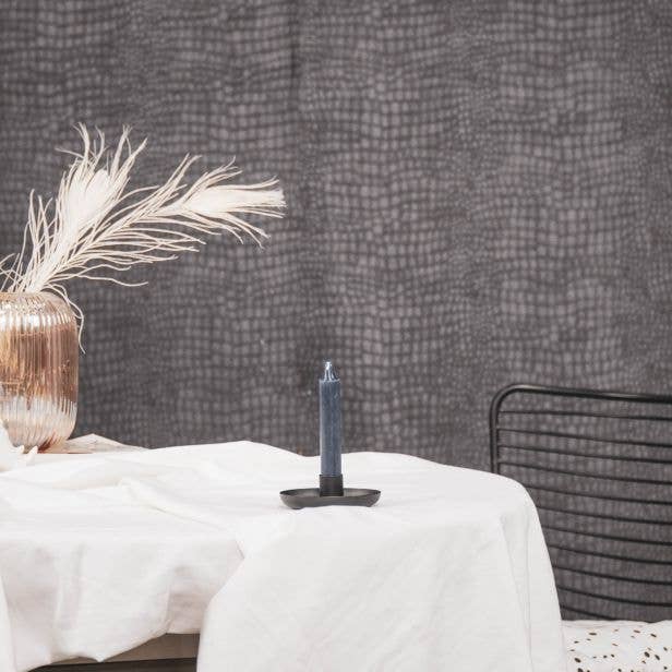 blue candle in a black candle holder on a round table with a white table cloth