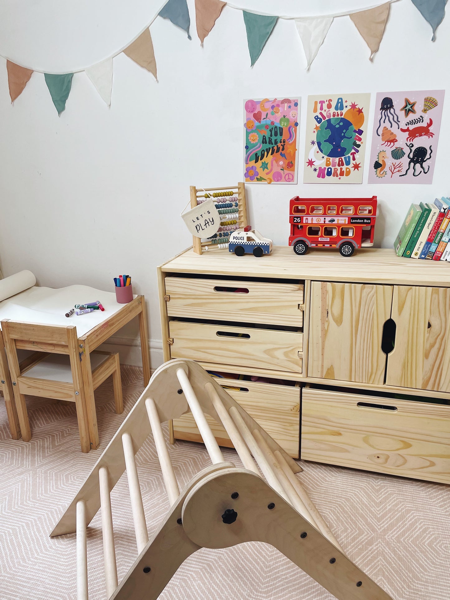 children's play area with storage, climbing frame, table and chairs, books, toys and pastel bunting