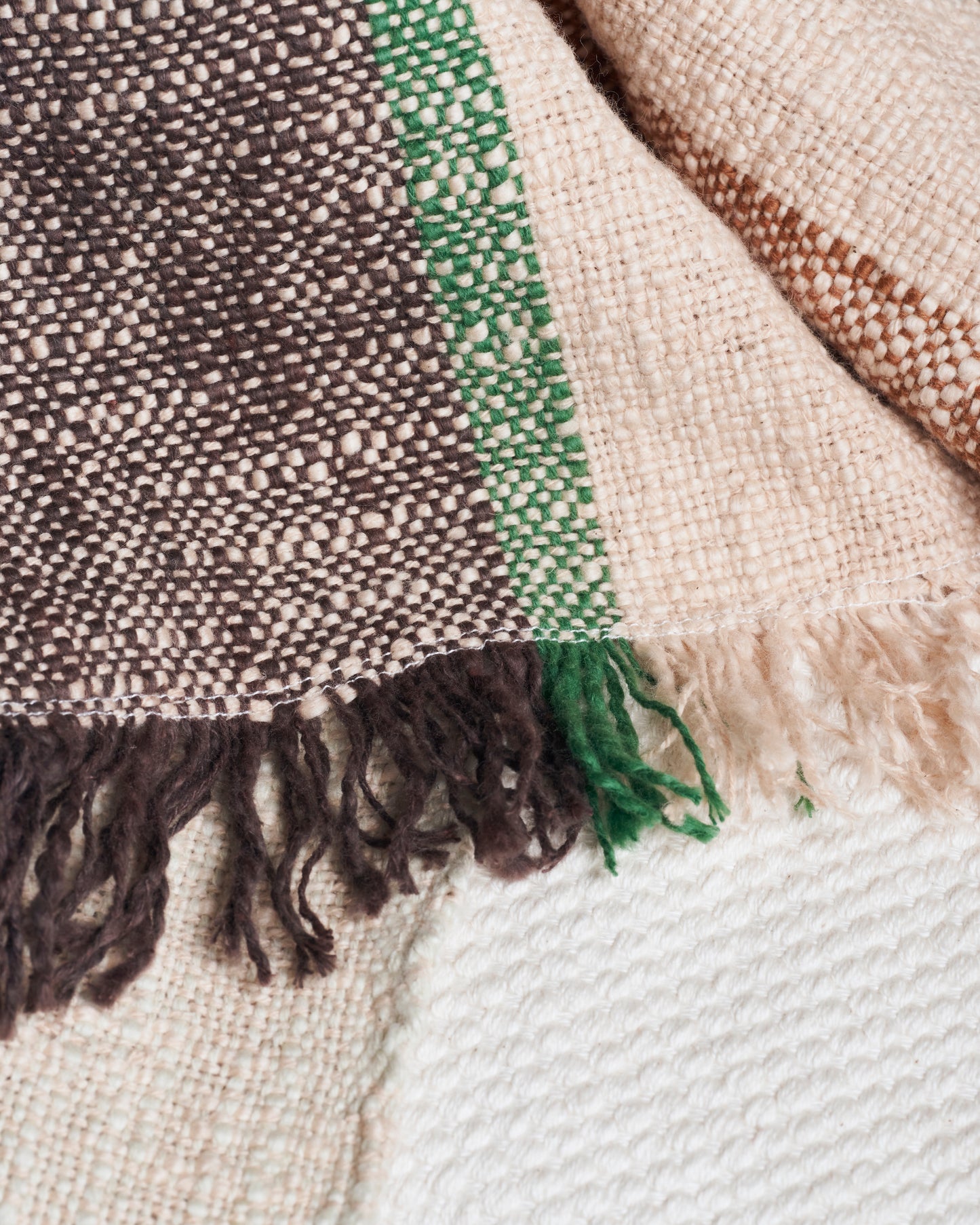 close up of multicoloured cotton throw with fringing in beige, brown and green