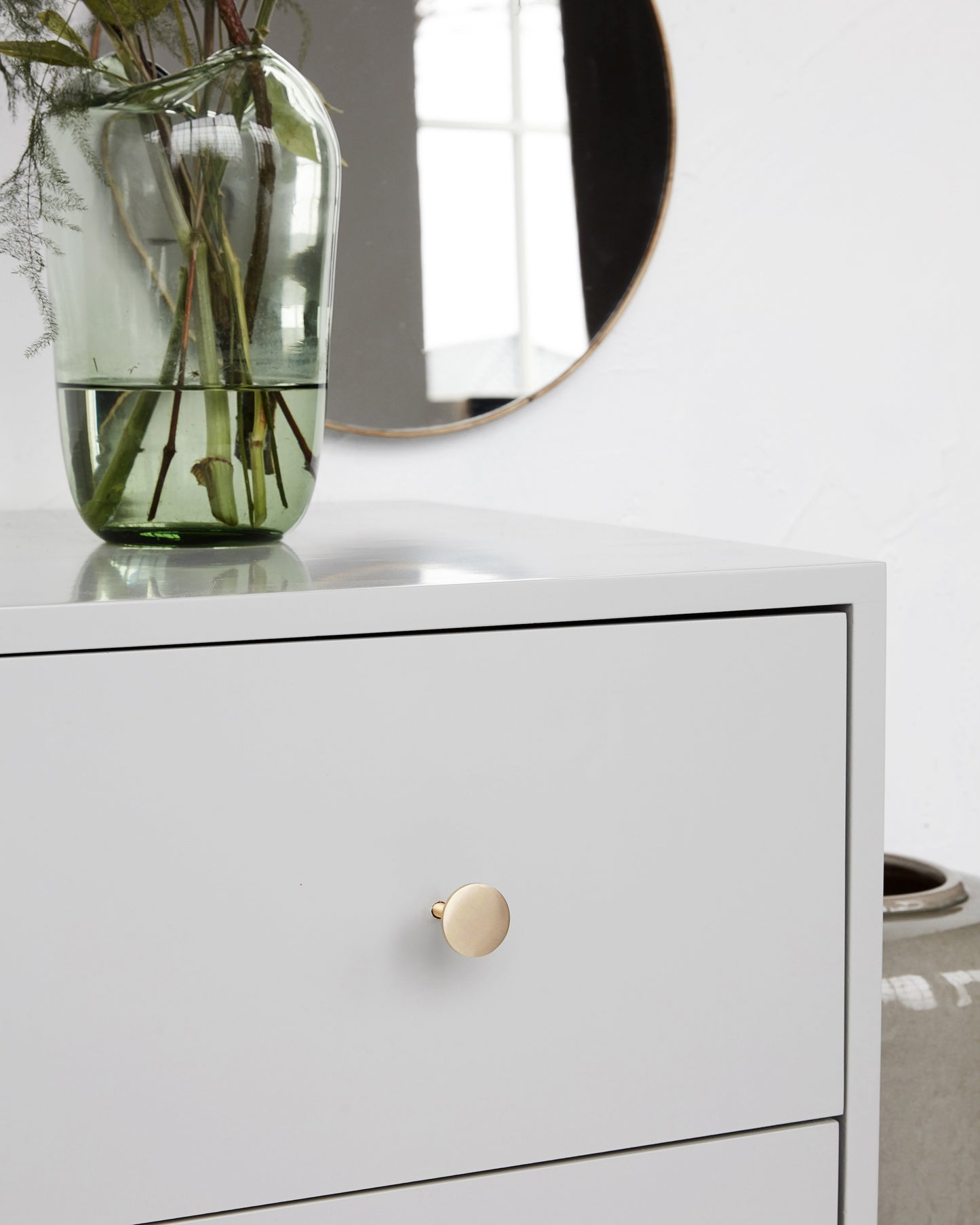 close up of grey chest of drawers with plain gold brass handle (round)
