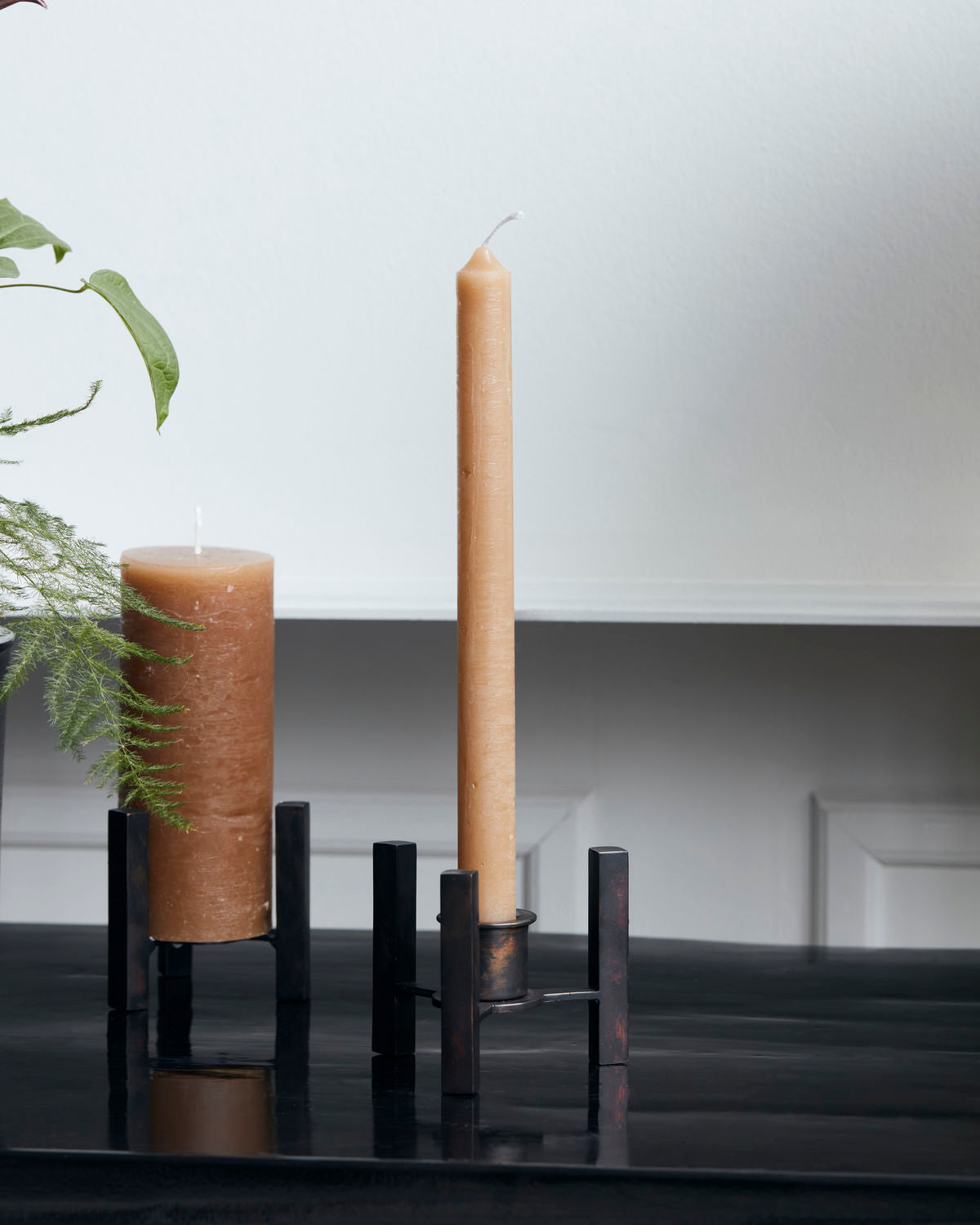 one tall and slim camel coloured candle and one smaller and wider