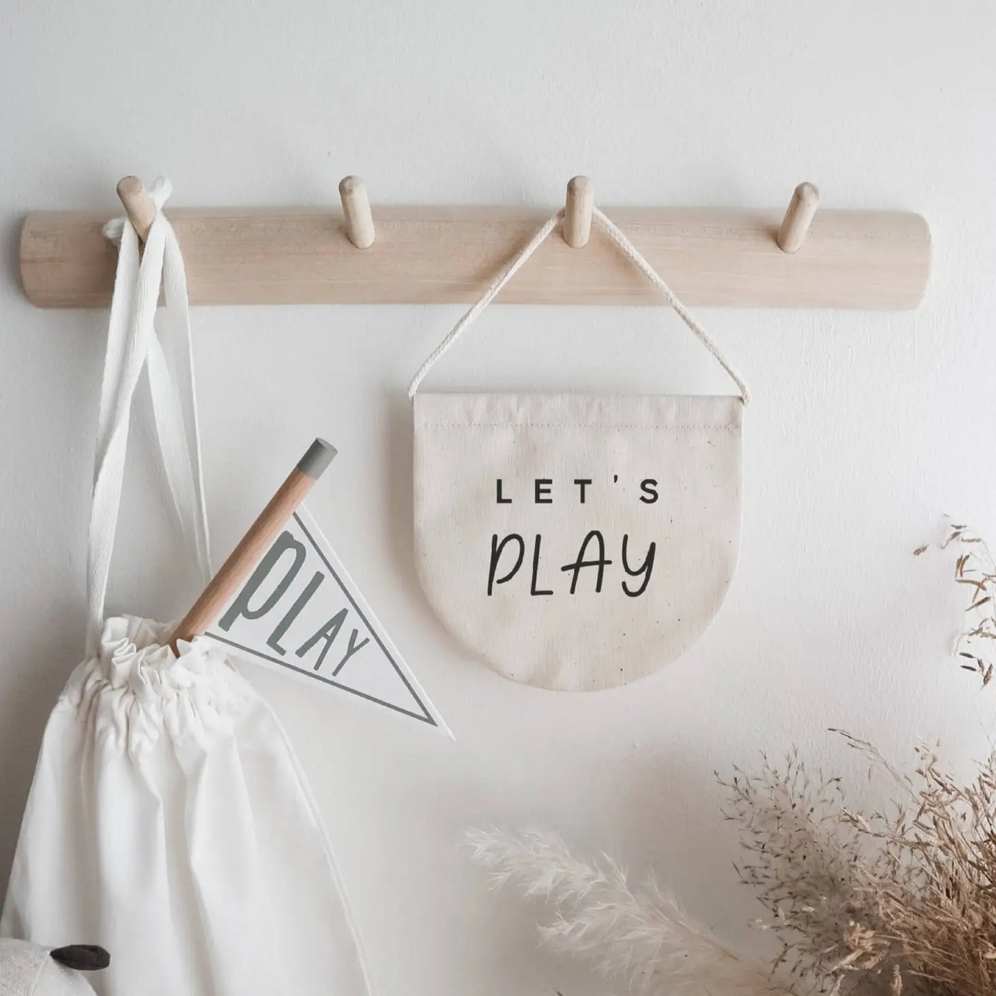 neutral wood hook with beige banner hanging from it, reading 'Let's Play'