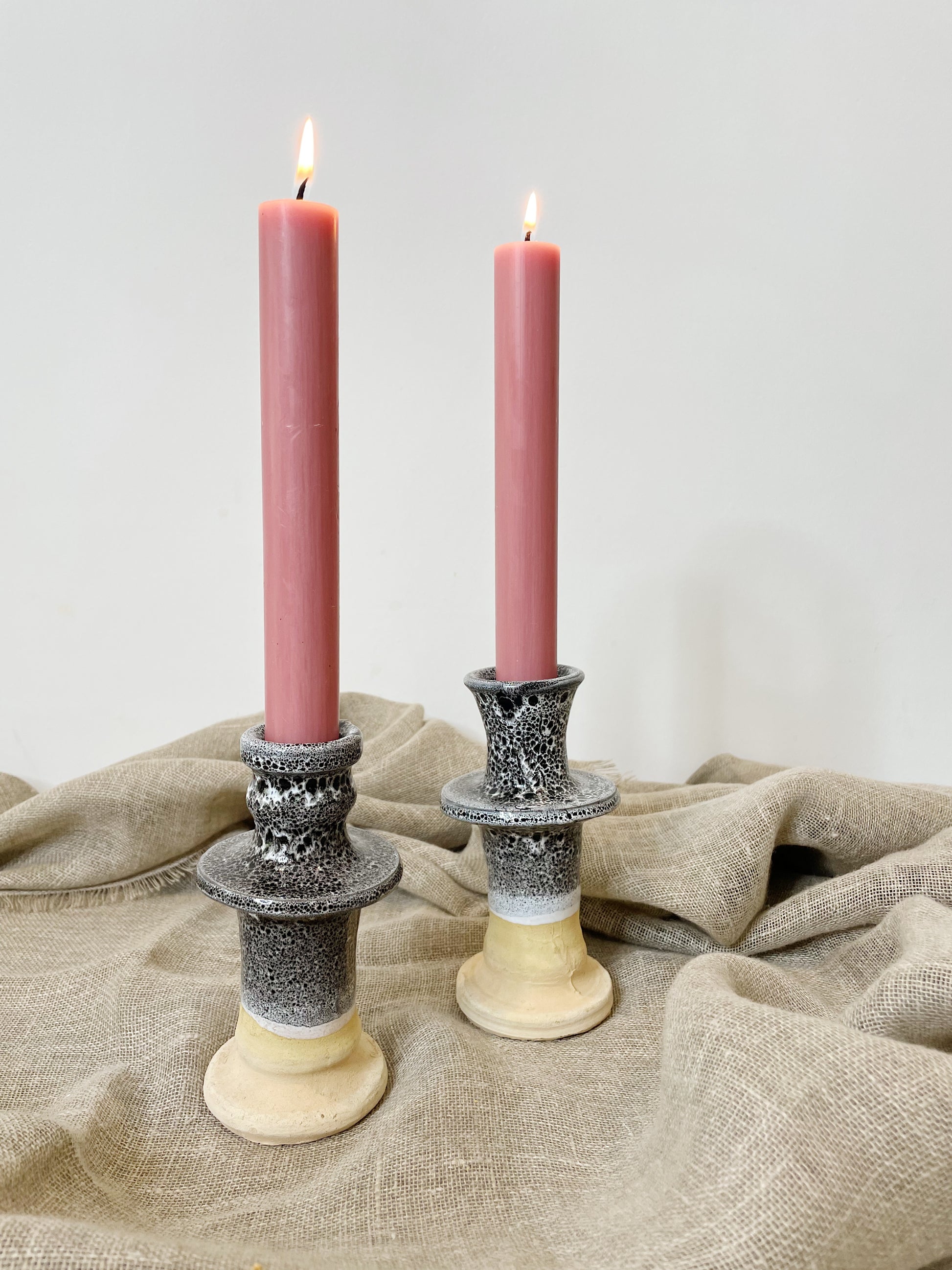 pink candles in blue and natural clay candle sticks