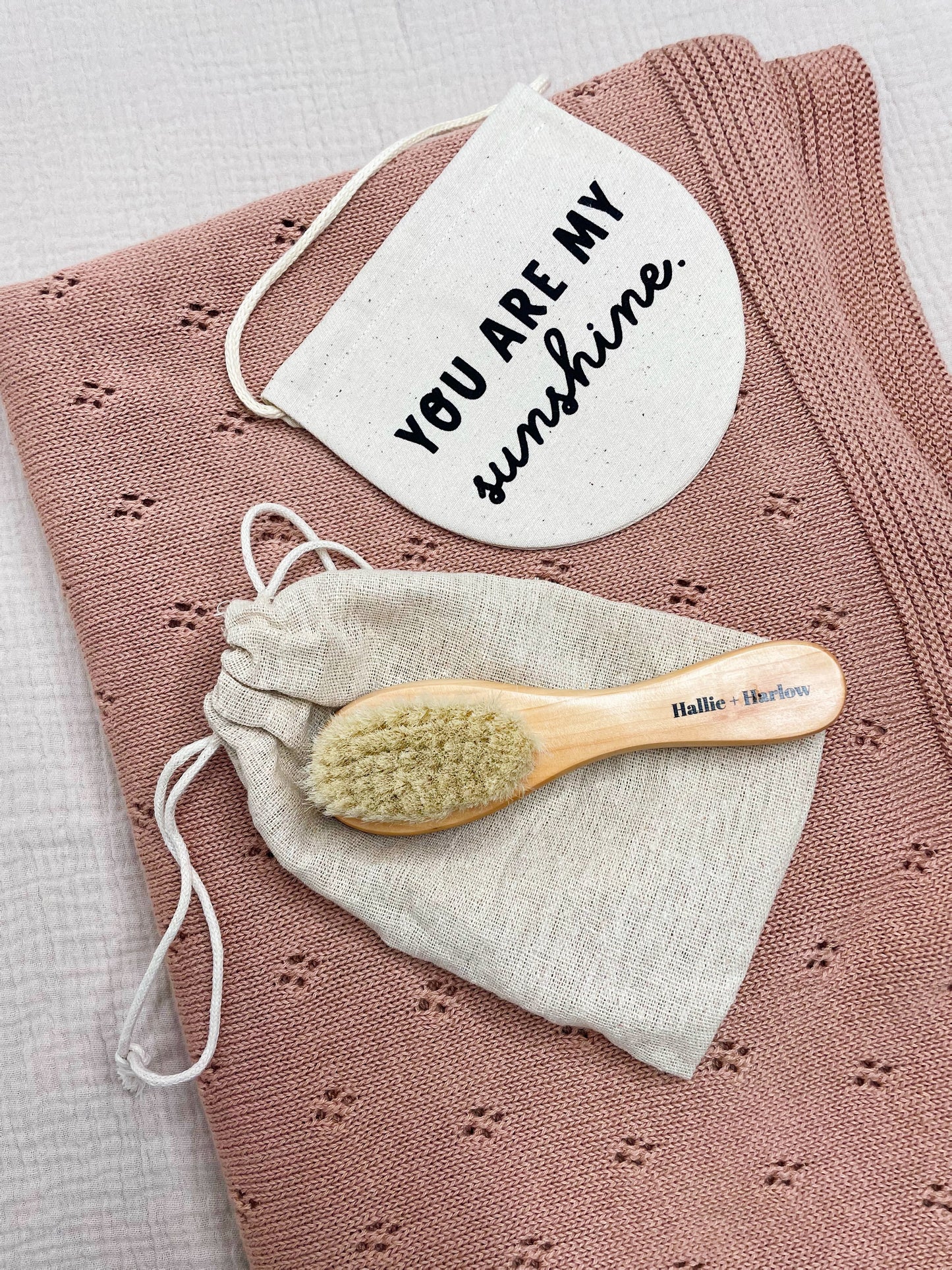 knitted cotton blanket in almond, with a baby hairbrush and a 'you are my sunshine' sign on top