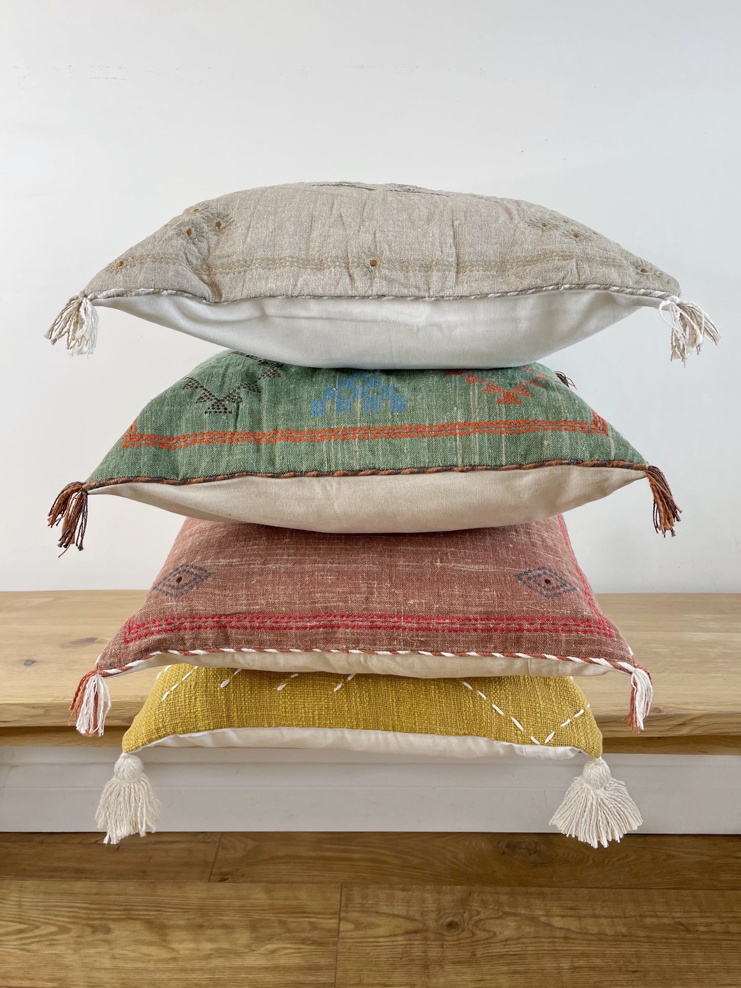 pile of four colourful cushions on a bench