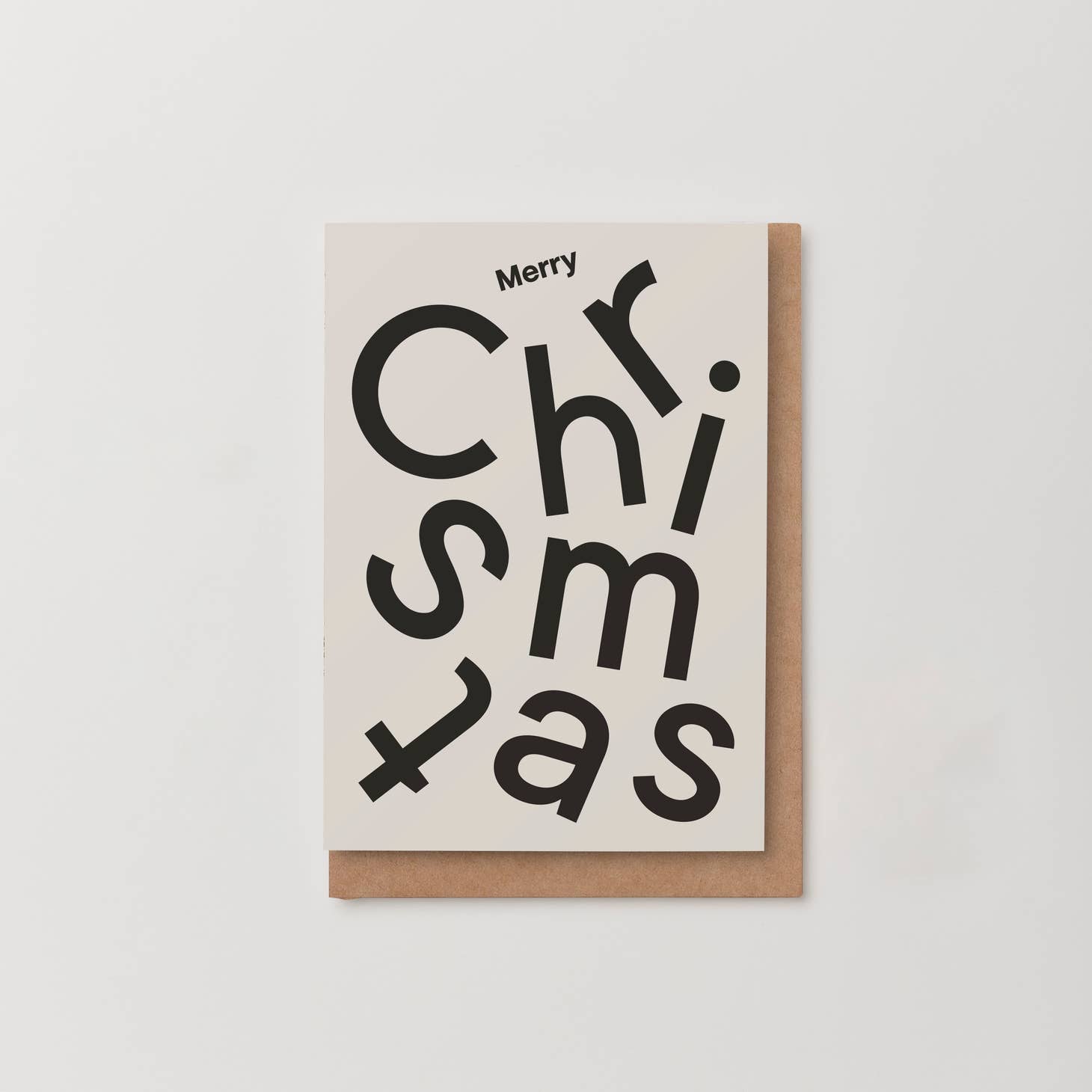 With greeting card with 'Merry Christmas' written on the front in a jumble of black letters