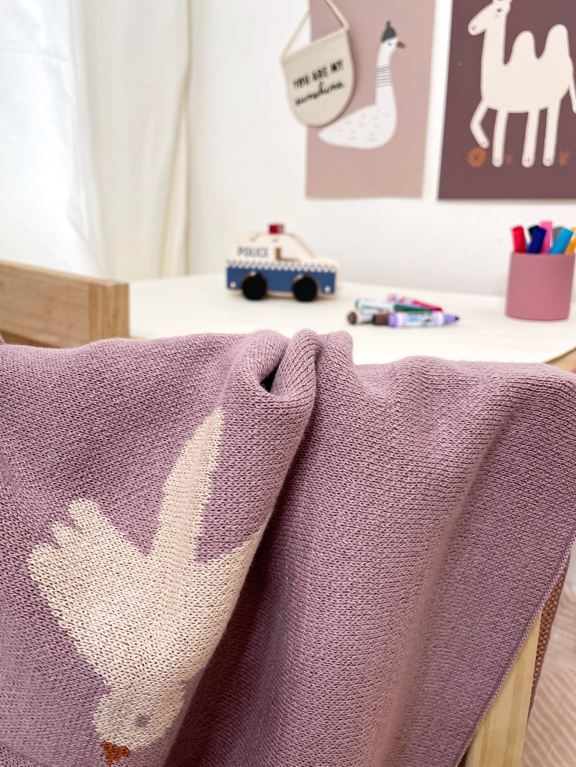 close up of a purple blanket with a white bird, with a child's play area in the background