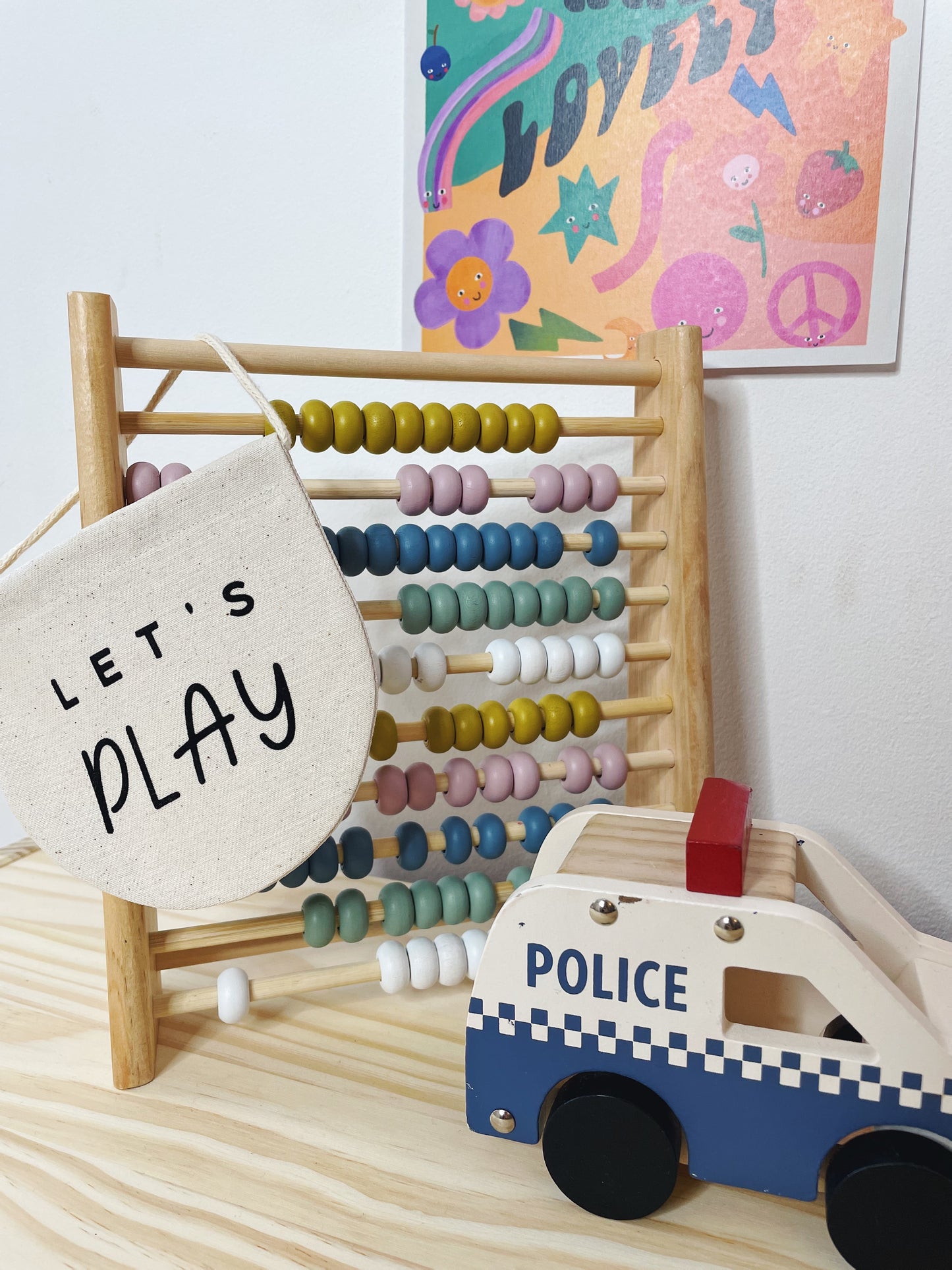 Colourful abacus, print and toy, with a beige banner hanging off the abacus, reading 'Let's Pla'