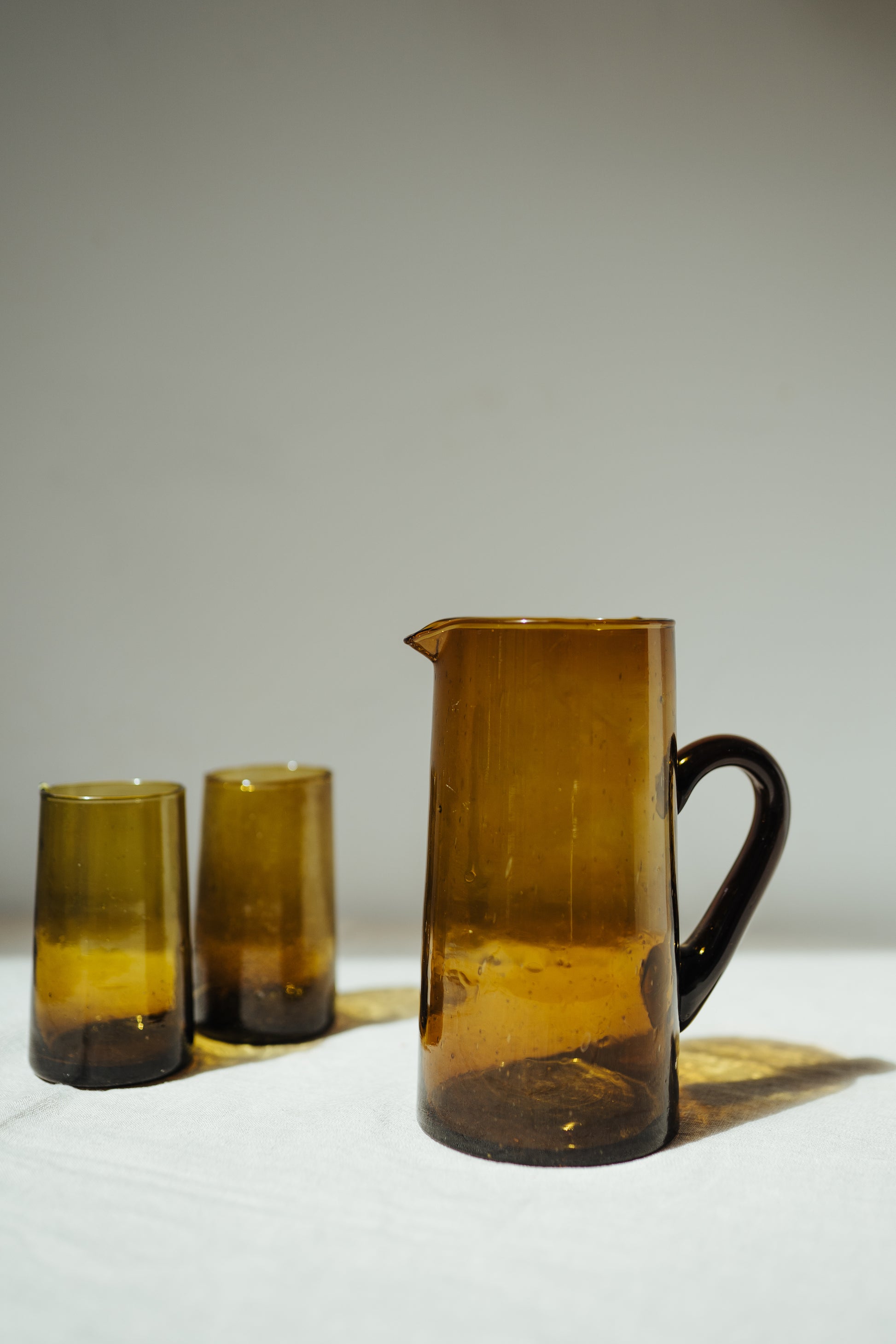 yellow brown glass jug with handle with two glasses in the same colour