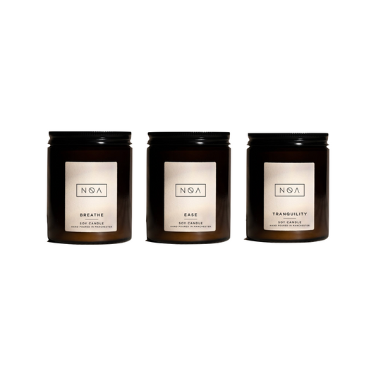 set of three candles, each in brown glass jars with a cream label with simple text detailing the candle names