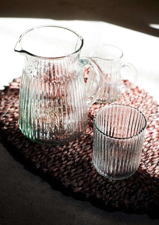clear glass jug with grooves, next to a matching glass